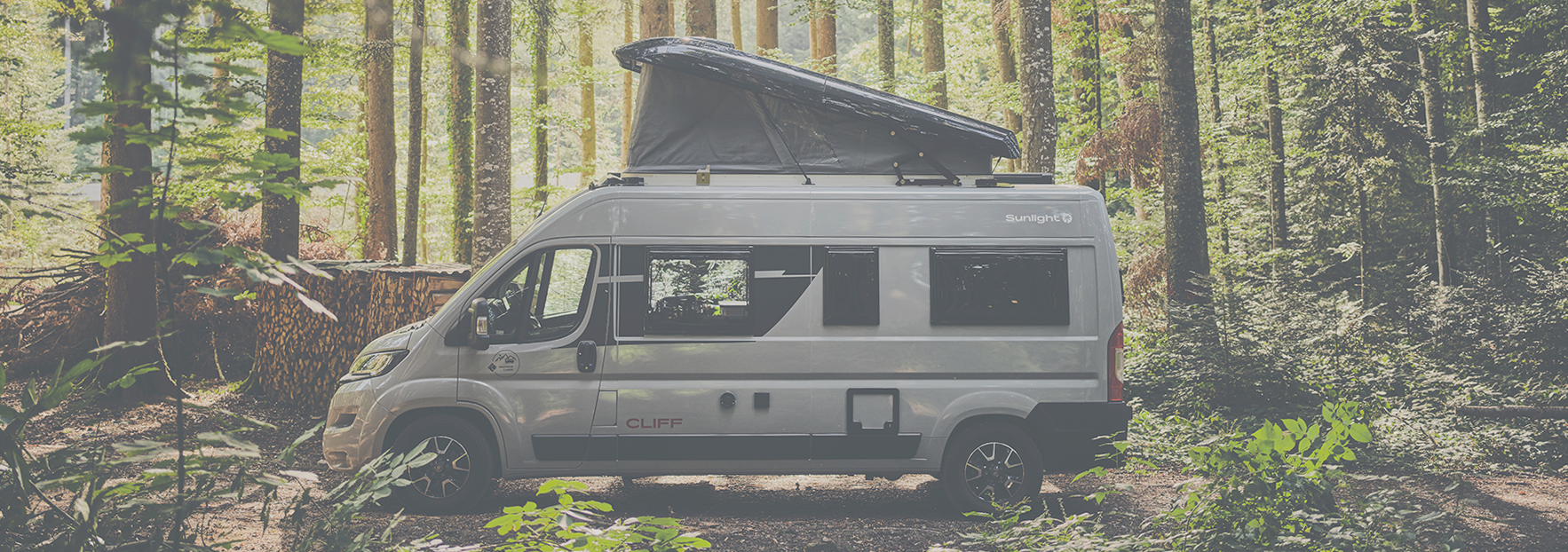 Sunlight CLIFF 600 Adventure mit Schlafdach, steht im Wald, zwischen Bäumen, Abenteuer, Outdoor-Camping, Miet-Camper